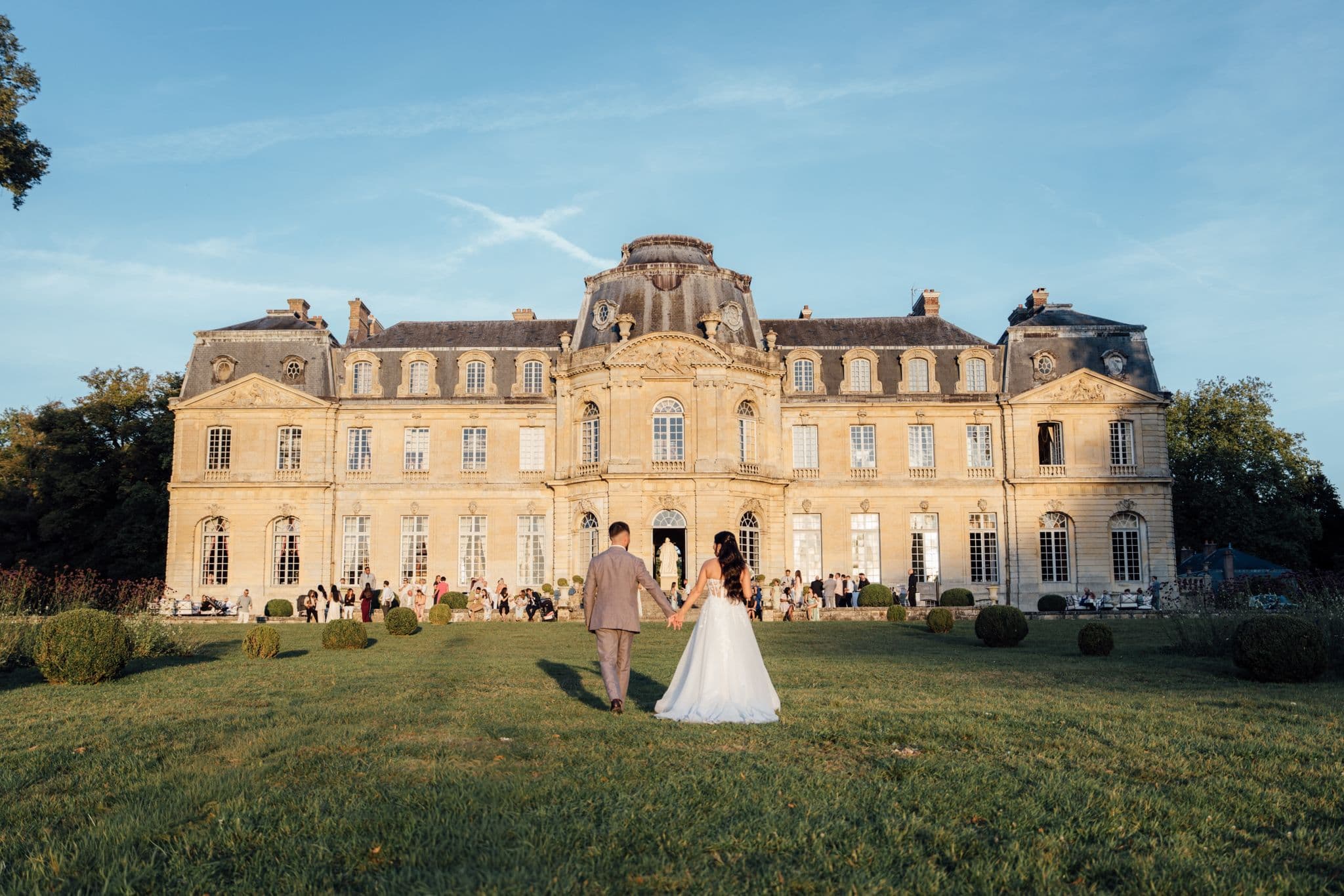mariés marine et maxime marchant devant le château de champlatreux