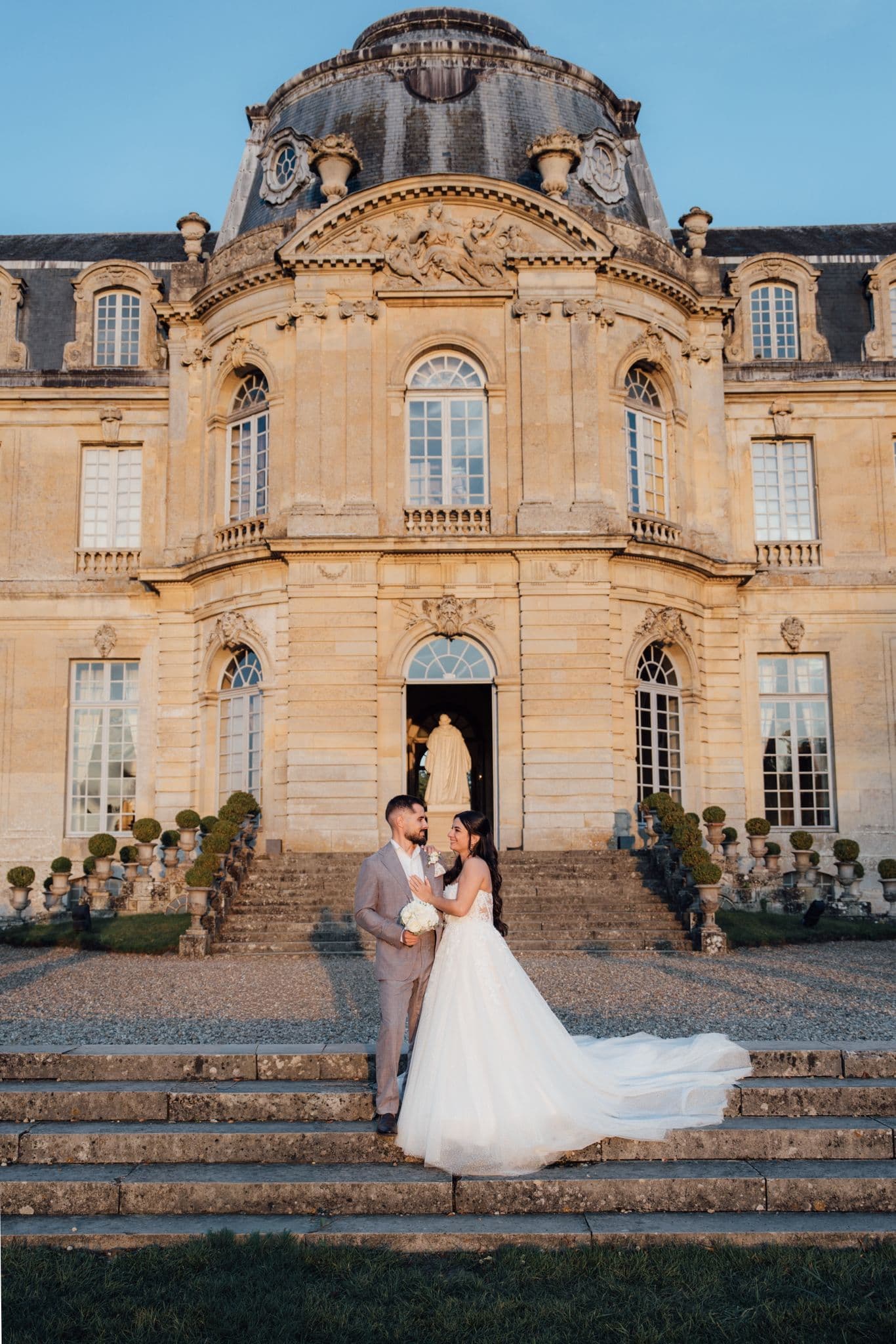 mariés marine et maxime posant devant le sublime château de champlatreux