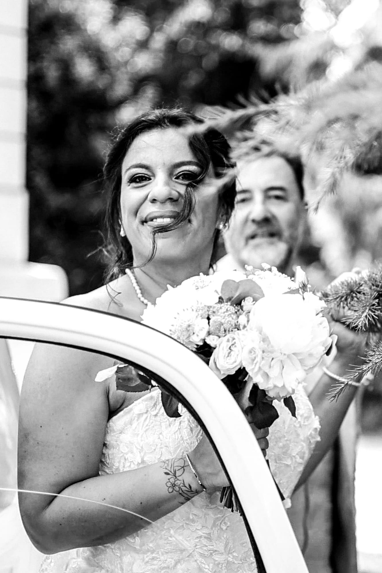 mariée marie portrait en noir et blanc devant la voiture de mariage