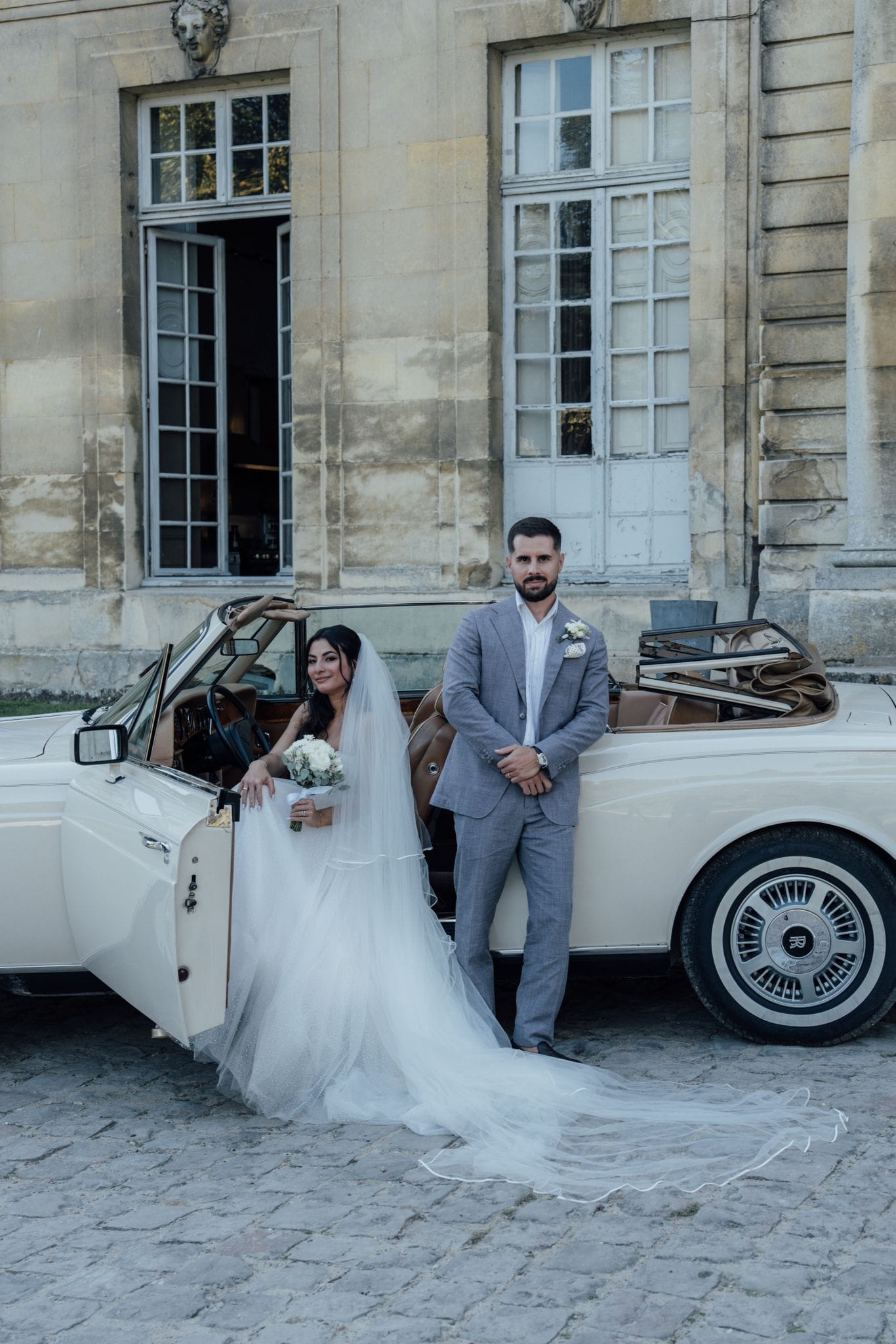 mariés marine et maxime posant dans la rolls royce devant le château de champlatreux