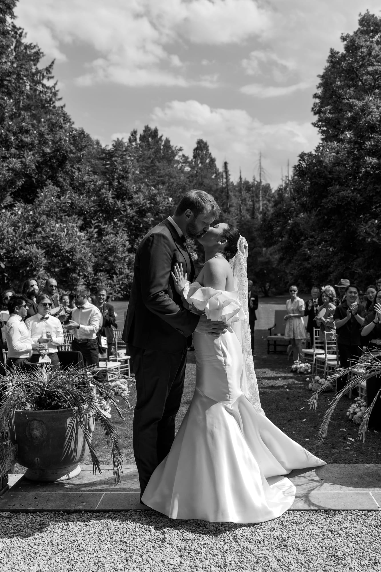 mariés yixiao et sean premier baiser en noir et blanc devant leurs invités