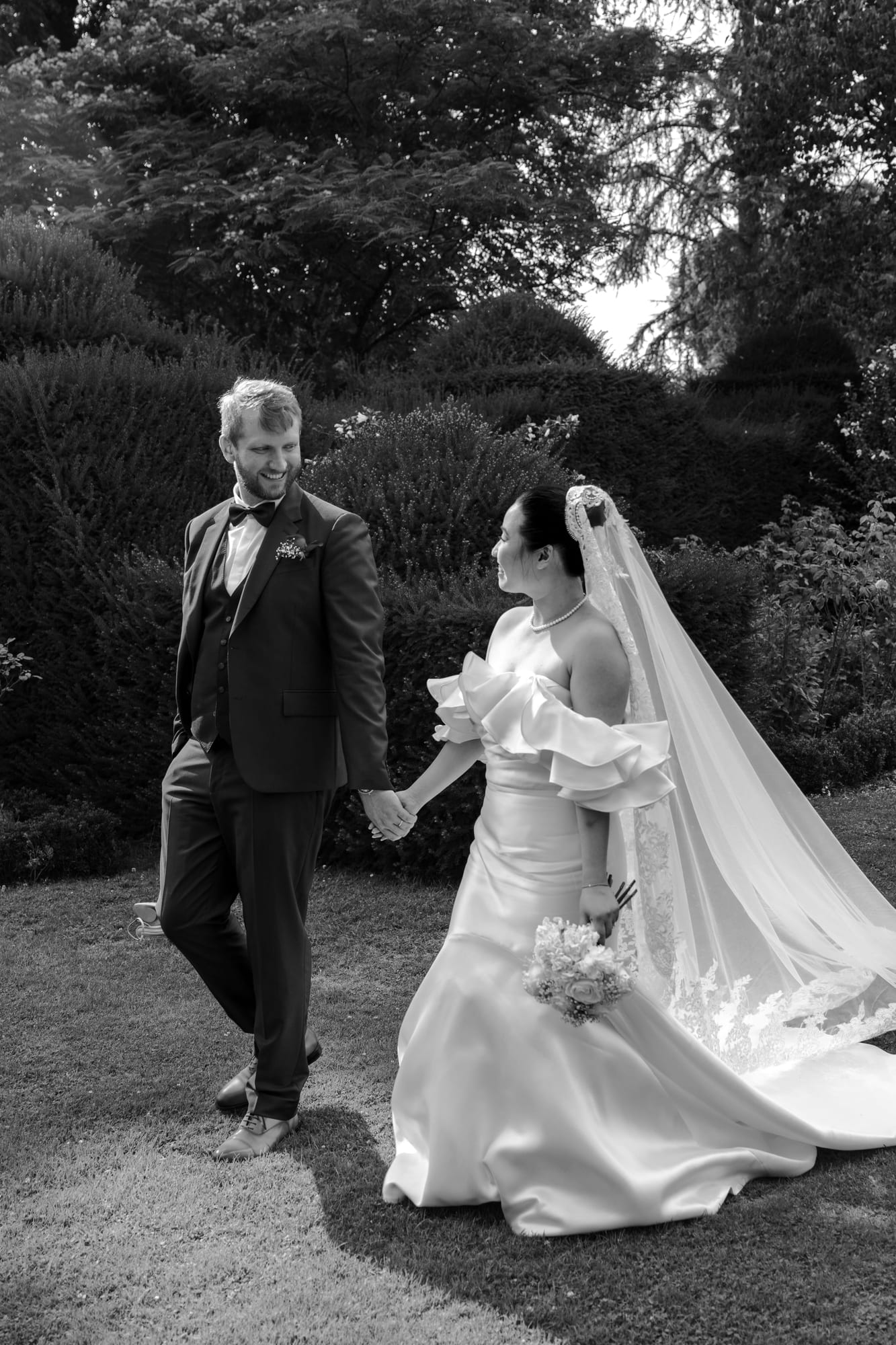 mariés yixiao et sean portrait en noir et blanc main dans la main dans les jardins