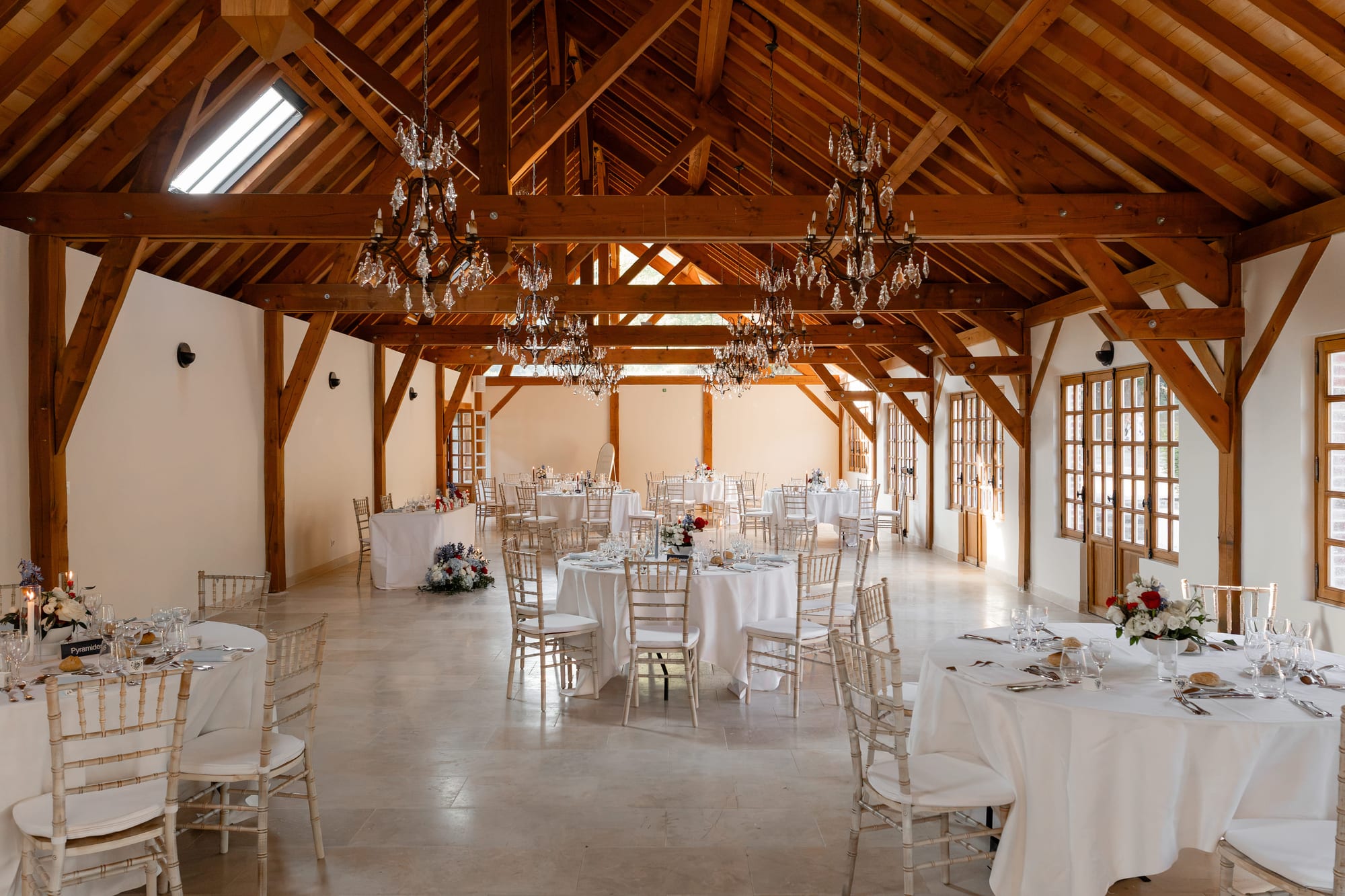 salle de réception sous charpente avec lustres en cristal aux jardins du grand courtoiseau