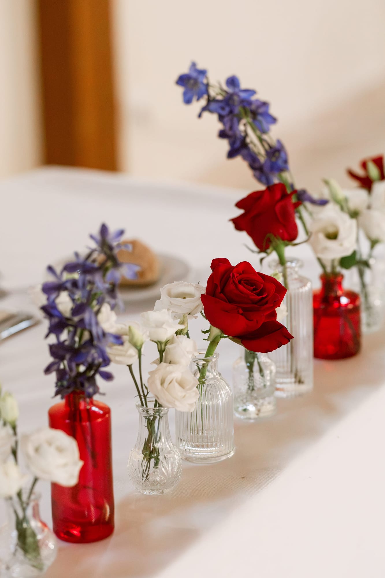 soliflores rouges et transparents garnis de roses rouges et de fleurs blanches sur la table d'honneur